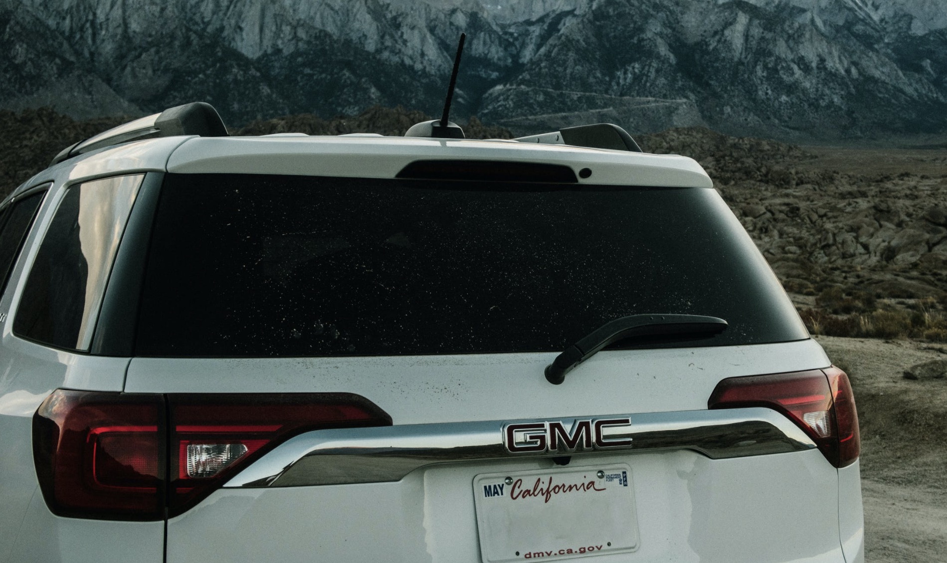 Back of a white GMC Crossover with overcast, night fall sweeping in.