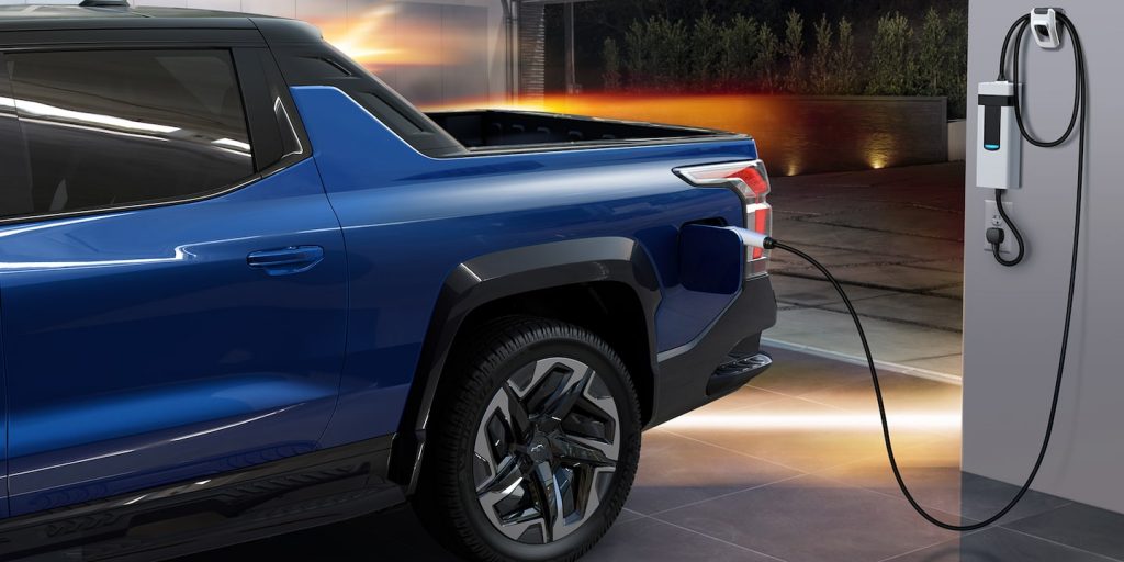 Image of a blue Chevrolet Silverado EV charging in an upscale garage at night 